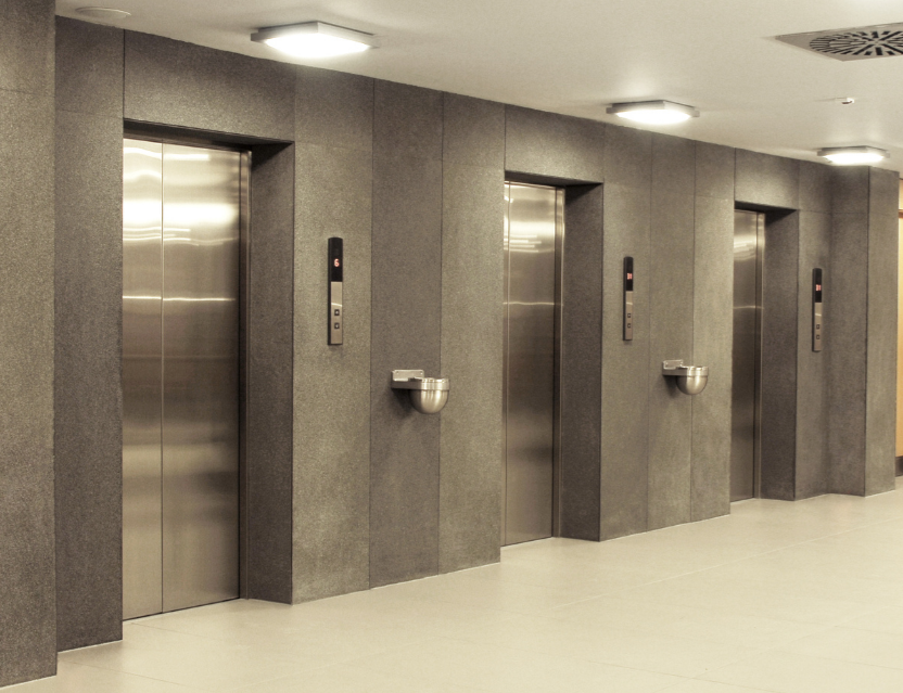Hệ thống ba thang máy cửa inox hiện đại trong sảnh tòa nhà văn phòng